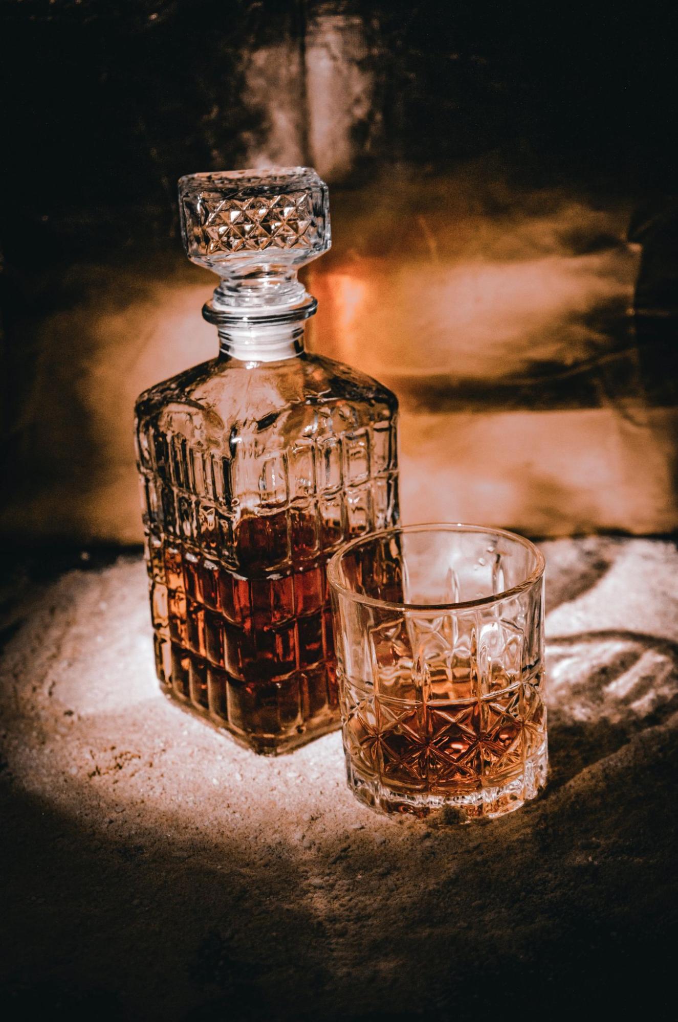 A decanter and glass filled with whiskey on a table.