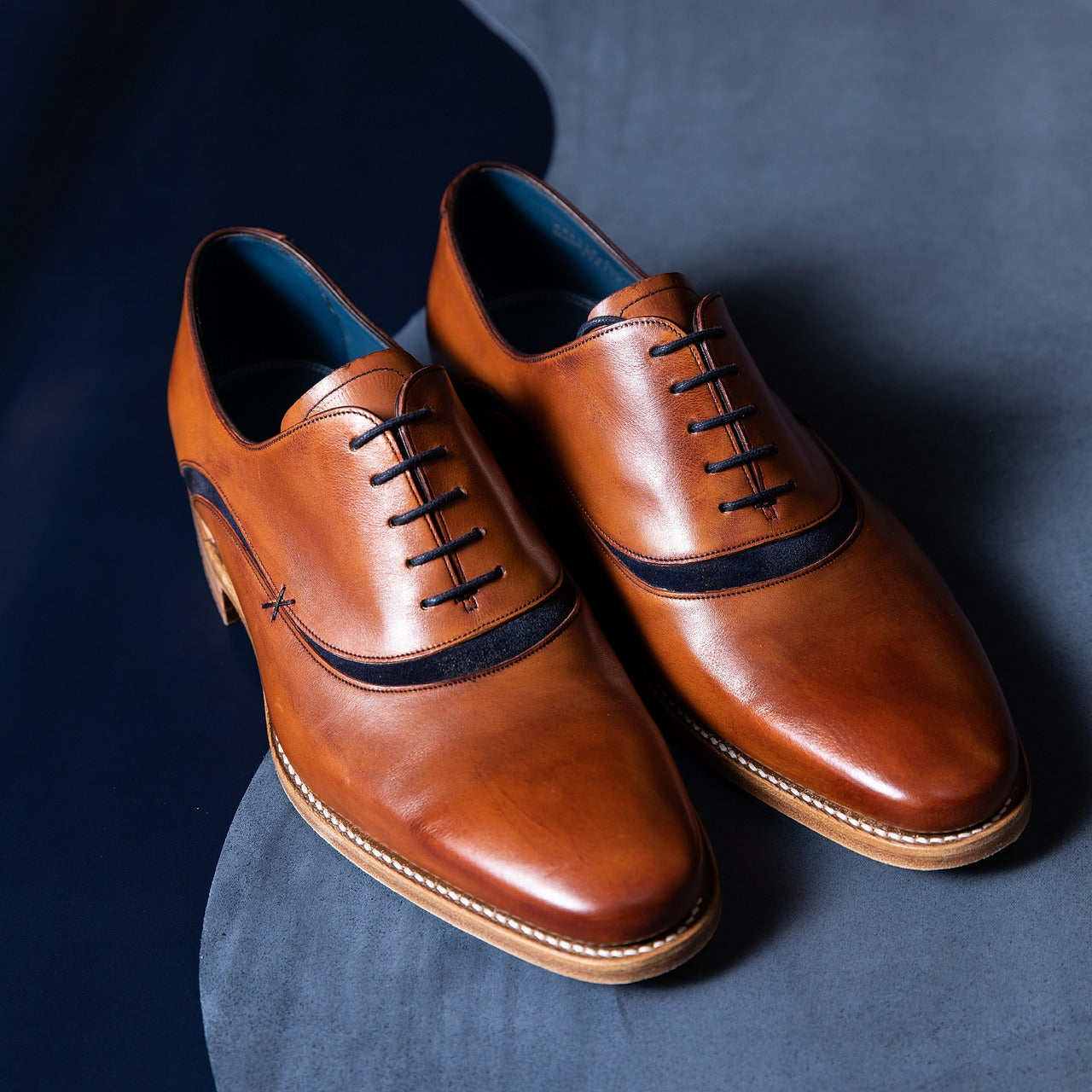 A pair of brown shoes on a gray floor.