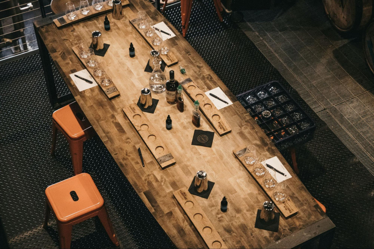 A large wooden table covered with whiskey bottles and silverware.