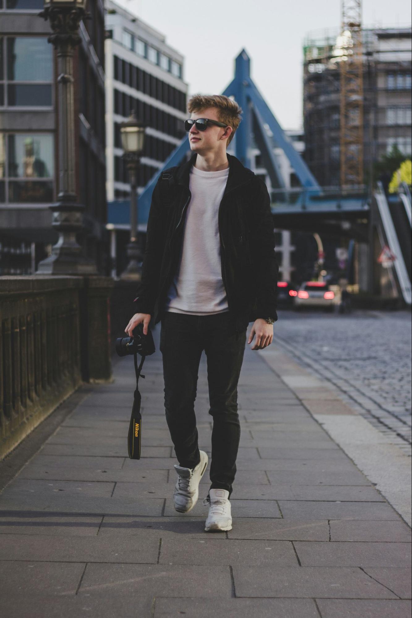 A man wearing sunglasses walks in a city.