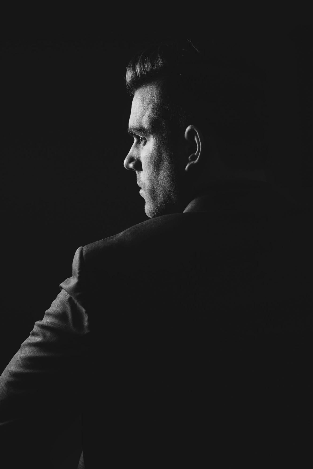 A man in a dark room looking toward a light.