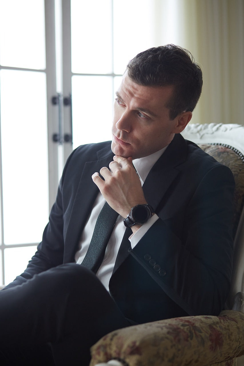 A man in a suit is sitting in a chair near a window.